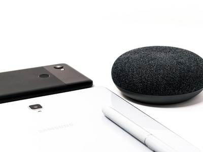 圆形黑色便携式无线扬声器和白色背景的黑色智能手机